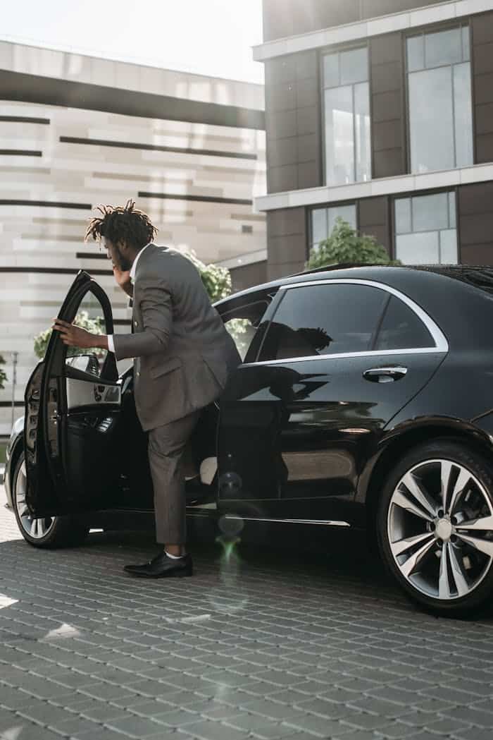 Hombre chófer con traje gris entrando en el taxi negro